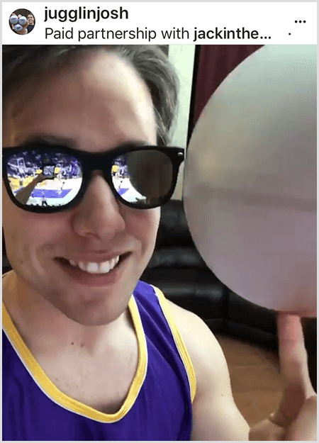 Josh Horton, Jack in the Box ve LA Lakers ile bir kampanya için bir fotoğraf paylaşır. Josh, aynalı güneş gözlüğü ve Lakers forması giyiyor ve top döndürürken kameraya gülümsüyor.